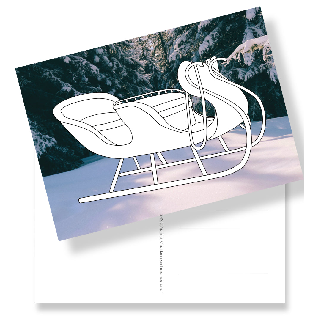 Postkarte in DIN A5 Format mit einem Schlitten-Ausmalmotiv auf winterlichen Fotohintergrund. Rückseite mit Adressfeld und weihnachtlicher Briefmarke. Eine wunderschöne Art des Schenkens.