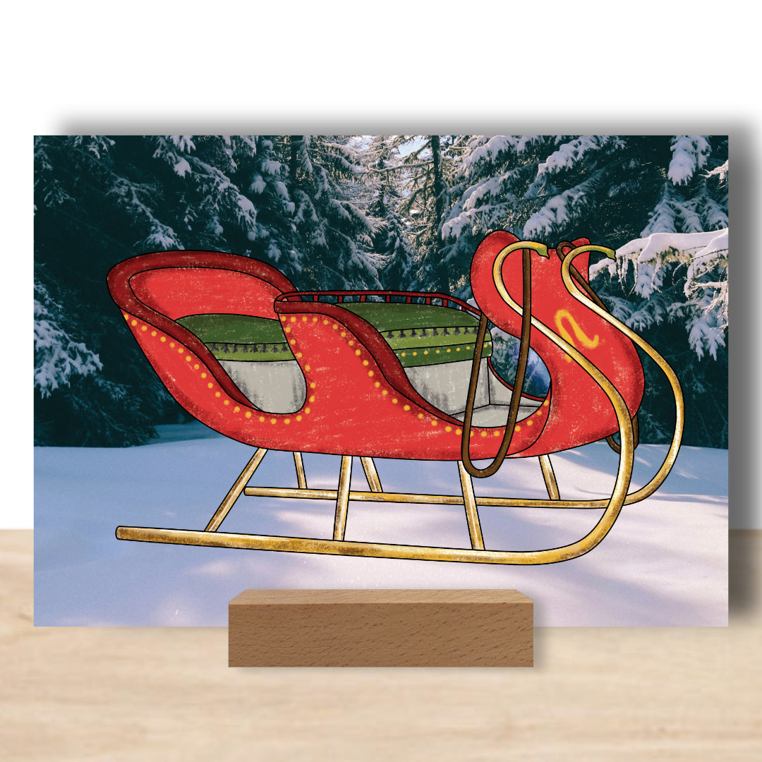 Postkarte mit ausgemalten Schlitten als Beispiel. Die Postkarte ist aufgestellt in einem Bilderhalter und ist ein wunderschönes weihnachtliches Accessoires.  