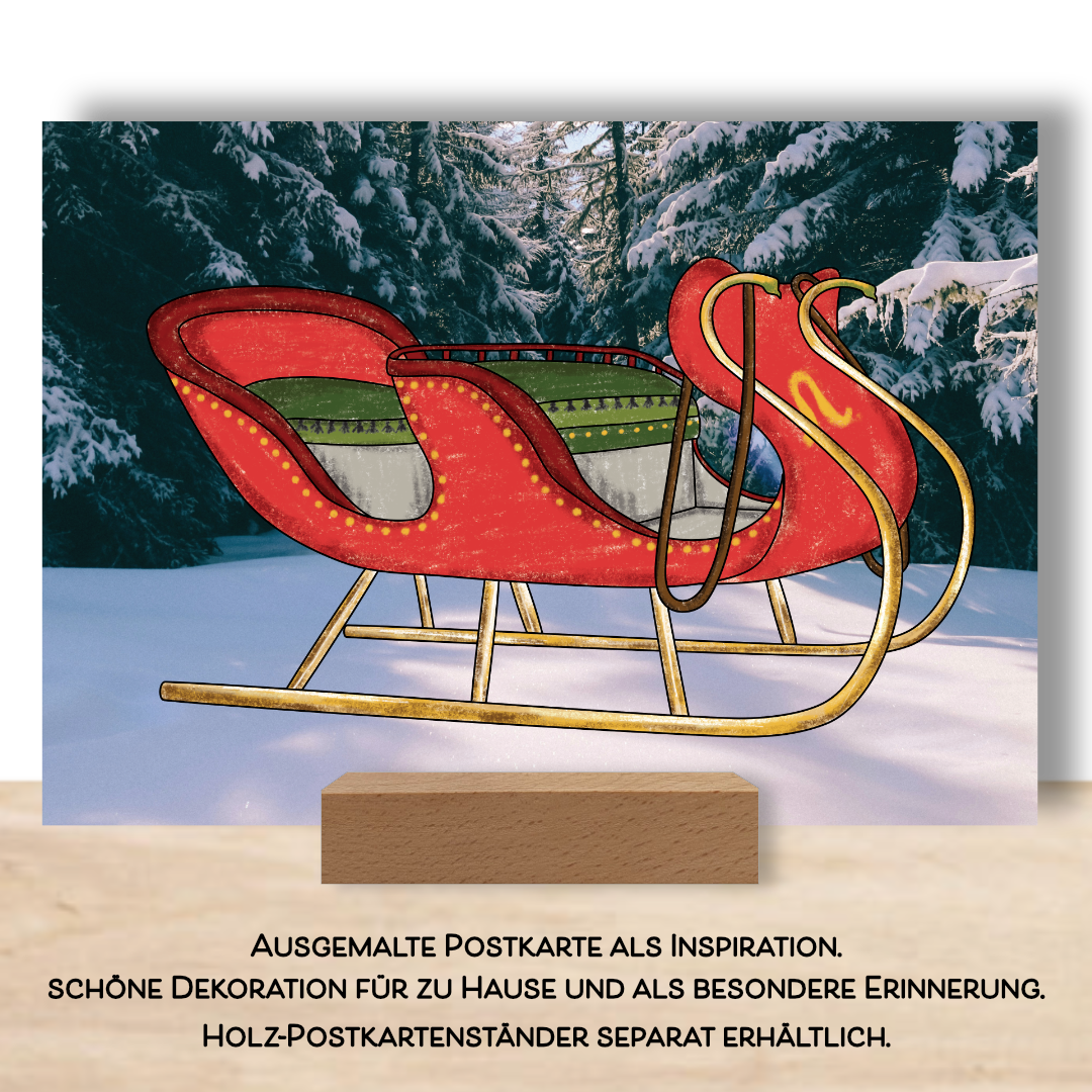 Ausgemalte Postkarte aus dem Postkarten Set "Weihnachtsglanz" Die Postkarte zeigt einen Schlitten der in rot und grün ausgemalt ist. Der Fotohintergrund zeigt eine winterliche Landschaft. Die Postkarte ist aufgestellt in einem Postkartenständer. 