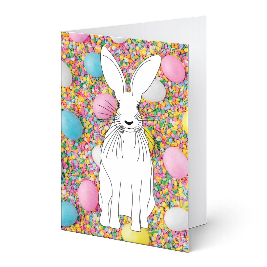Grußkarte aus dem Ostergrußkarten-Set "Hasenglück & Eierspaß" zum Ausmalen auf Fotohintergrund. Detaillierter Hase als Ausmalvorlage vor einem bunten Fotohintergrund aus Zuckerstreusel und pastellfarbenen Ostereiern.