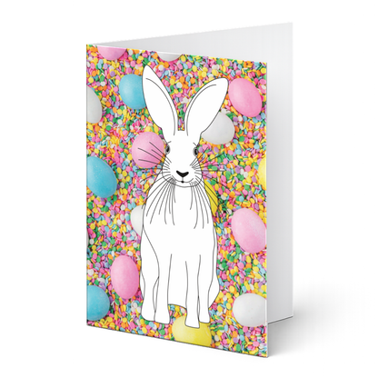 Grußkarte aus dem Ostergrußkarten-Set "Hasenglück & Eierspaß" zum Ausmalen auf Fotohintergrund. Detaillierter Hase als Ausmalvorlage vor einem bunten Fotohintergrund aus Zuckerstreusel und pastellfarbenen Ostereiern.