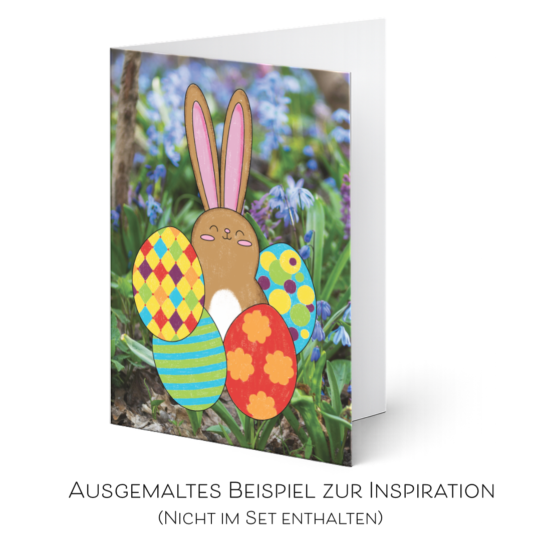 Inspirationsbeispiel einer fertig ausgemalen österlichen Grußkarte mit einem braunen Hasen und bunten Ostereiern in Rot, Blau, Grün und Gelb vor einem Fotohintergrund aus blauen Frühlingsblumen. Die ausgemalte Karte ist nicht im Set enthalten.