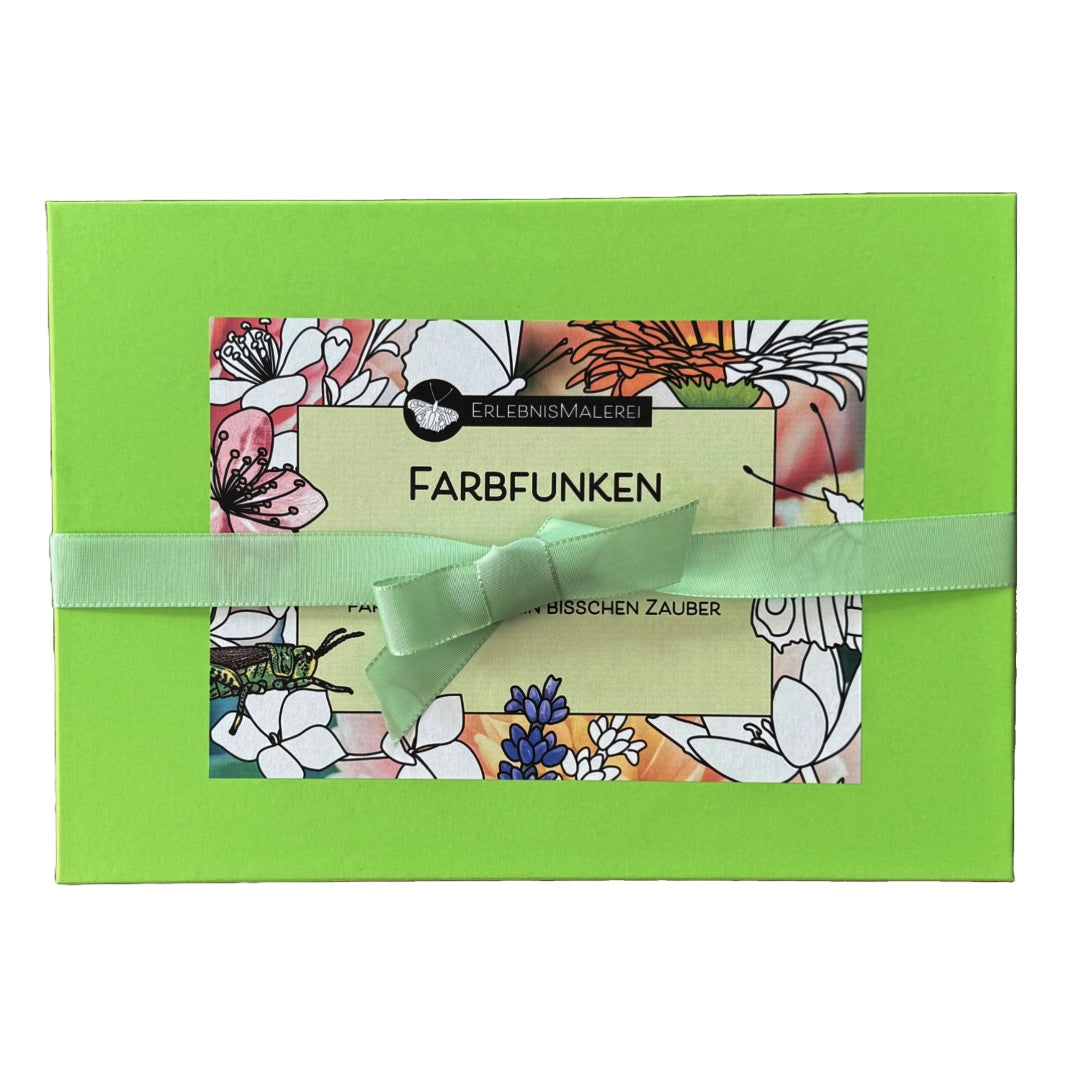 Geschenkset "Farbfunken"von ErlebnisMalerei. Grüne Geschenkschachtel mit Schleife, gefüllt mit Malkarten, Buntstiften, Bilderhaltern und einer kleinen Überraschung für kreatives Ausmalen.