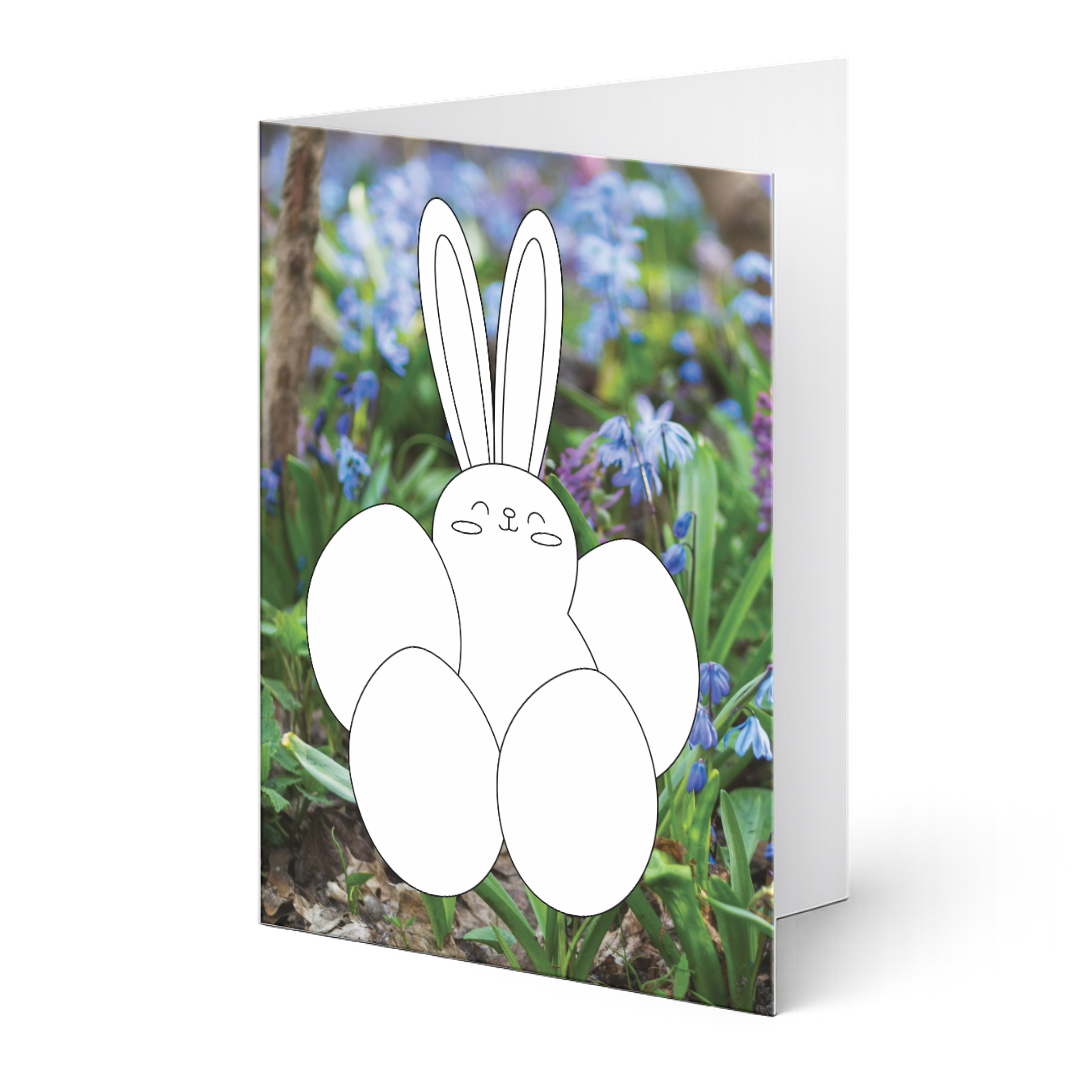 Oster-Grußkarte aus dem Grußkartenset "Hasenglück & Eierspaß" zum Ausmalen auf Fotohintergrund. Niedlicher Hase mit Eiern als Ausmalvorlage auf einem Fotohintergrund mit blauen Frühlingsblumen.