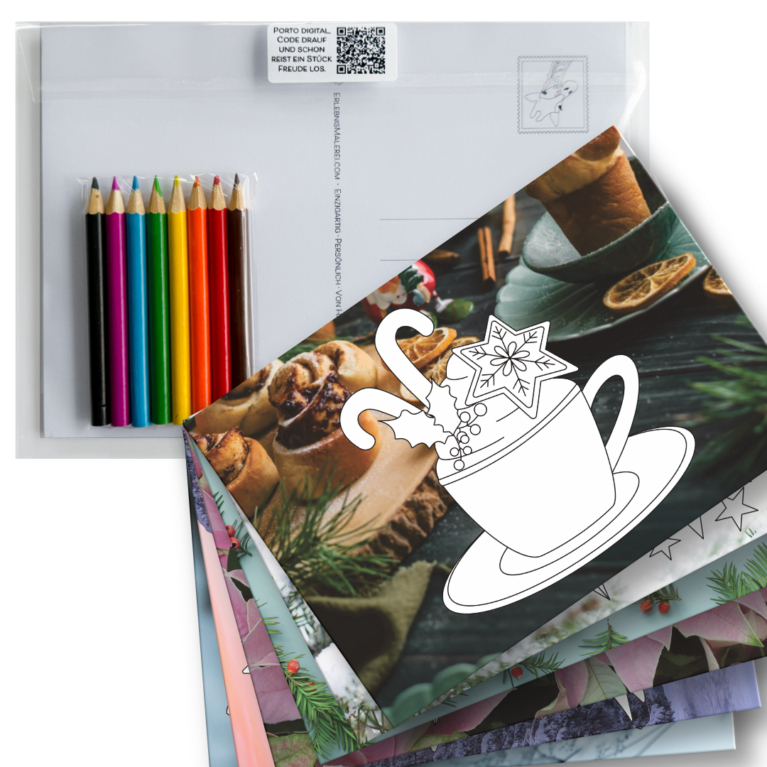 Weihnachtliches Postkarten-Set zum Ausmalen auf Fotohintergrund und 8 Buntstiften. Gezeigt werden  die weihnachtlichen Ausmalbilder gefächert und obenauf liegt eine Postkarte mit dem Ausmalbild einer Tasse mit Zuckerstangen, Stern und Mistelzweig. 